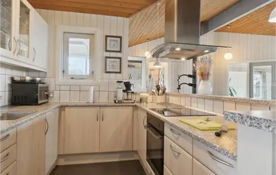 a large kitchen with wooden cabinets and a sink at Stunning Home In Vestervig With Sauna in Vestervig