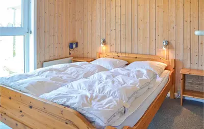 a large wooden bed with white sheets in a room at Stunning Home In Thisted With Sauna in Thisted