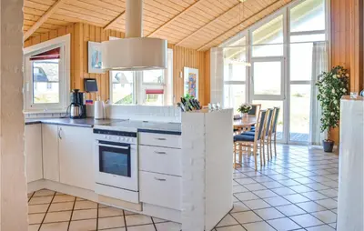 a kitchen with white appliances and a dining room with a table at Stunning Home In Thisted With Sauna in Thisted