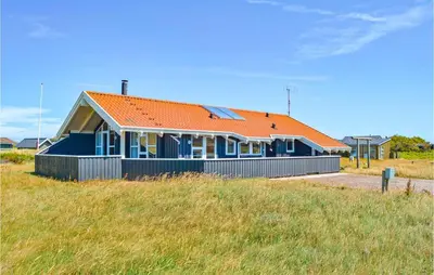 a blue house with an orange roof on a field at Stunning Home In Thisted With Sauna in Thisted