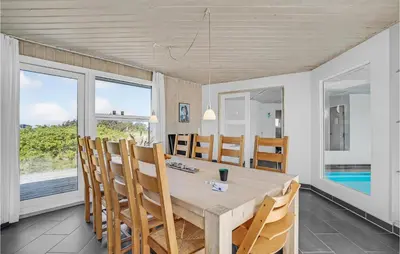 a dining room with a table and chairs and windows at Stunning Home In Thisted With Sauna in Thisted