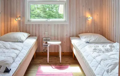 two beds in a room with a table and a window at Three-Bedroom Holiday Home In Thisted in Thisted