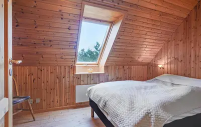 a bedroom with wooden walls and a bed with a window at Four-Bedroom Holiday Home In Thisted in Thisted