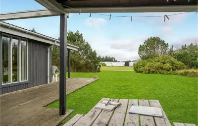 a backyard with a wooden deck and a lawn at Holiday Home Klemsvej in Thisted