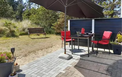 a patio with a table and chairs and an umbrella at Holiday Home Grårisvej Thisted V in Thisted