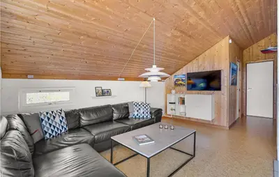 a living room with a leather couch and a table at Holiday Home Grårisvej Thisted Vi in Thisted