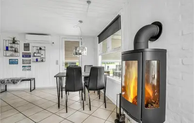 a fireplace in a kitchen with a table and chairs at Holiday Home Fiskervej Thisted Iv in Thisted