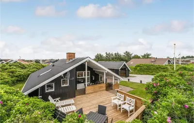 a black house with a deck and chairs at Holiday Home Fiskervej Thisted Iv in Thisted