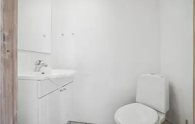a white bathroom with a toilet and a sink at Holiday Home Ørredvej Thisted Ii in Thisted