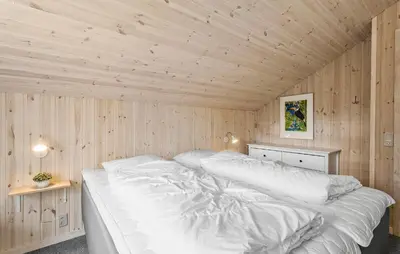 a bedroom with a white bed in a wooden wall at Holiday Home Tranebærvej Thisted Iv in Nørre Vorupør