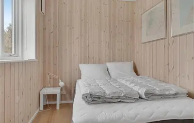 a bedroom with a bed with white sheets and a window at Holiday Home Stenbjerg Kirkevej in Snedsted