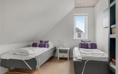 a small bedroom with two beds and a window at Holiday Home Stenbjerg Kirkevej in Snedsted