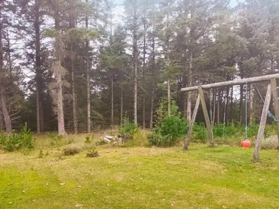a swing set in a field next to a forest at Charming Cottage near Beach - By Traum Ferienwohnungen in Fjerritslev
