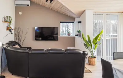 a black leather couch in a living room with a television at Holiday Home Gunhildsvej Vestervig Xi in Vestervig