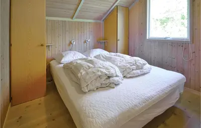 a bedroom with a bed with white sheets and a window at Holiday Home Gunhildsvej Vestervig in Vestervig