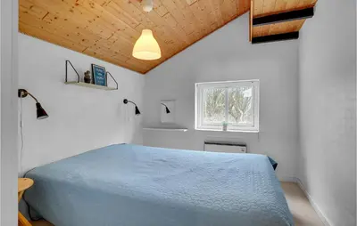 a bedroom with a blue bed and a window at Holiday Home Gunhildsvej Vestervig Vi in Vestervig