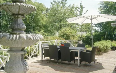 a table with chairs and an umbrella next to a fountain at Awesome Home In Spøttrup With Wifi in Spottrup