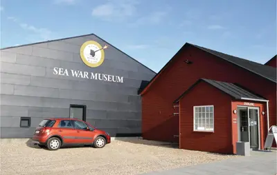 a red car parked in front of a red barn at Holiday Home Astersvej in Lemvig