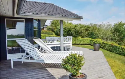 a pair of chairs and an umbrella on a deck at Holiday Home Skovstjernevej Lemvig Ii in Lemvig