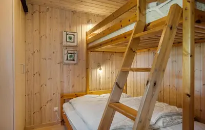 a bunk bed in a wooden room with a ladder at Holiday Home Sommerstedvej Denm in Vinderup