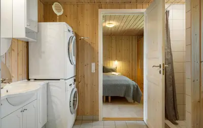 a bathroom with a washer and dryer and a bedroom at Holiday Home Sommerstedvej Denm in Vinderup