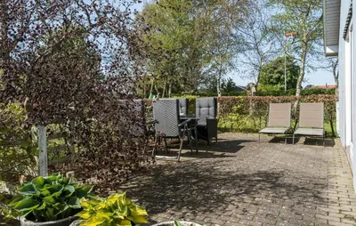 a patio with chairs and a table in a yard at Holiday Home Sommerstedvej Denm in Vinderup