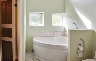 a white bathroom with a tub and a toilet at Holiday Home Ålbækparken Spøttrup Ii in Spottrup