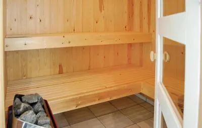 a sauna with wooden walls and a chair in a room at Holiday Home Ålbækparken Spøttrup Ii in Spottrup