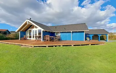 a blue house with a wooden deck in a yard at Holiday Home Lerskrænten Vinderup I in Vinderup