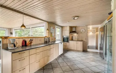 a large kitchen with wooden cabinets and a counter at Holiday Home Skibstedvej Hurup Thy in Sønder Ydby