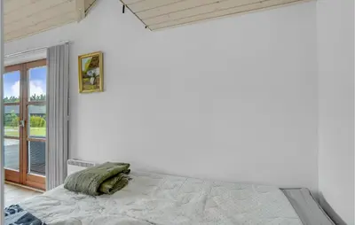 a white bedroom with a bed and a window at Holiday Home Skovvej Thyholm Xii in Thyholm