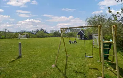 a playground with two swings in a field at Holiday Home Kalkstensvej in Spottrup