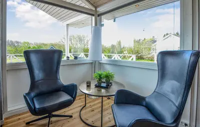 two chairs and a table in a room with windows at Holiday Home Kalkstensvej in Spottrup
