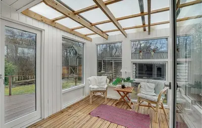 a screened porch with a table and chairs and windows at Holiday Home Hærvej Thyholm Xi in Thyholm
