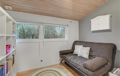a living room with a couch and two windows at Holiday Home Hærvej Thyholm Xi in Thyholm
