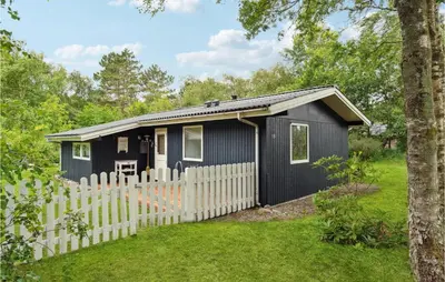 a black tiny house with a white fence at Holiday Home Hærvej Thyholm Xi in Thyholm