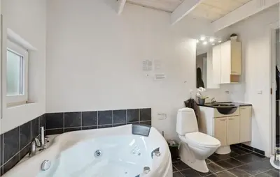 a bathroom with a white tub and a toilet at Lovely Home In Thyholm With Sauna in Thyholm