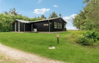 a small black building with a grass yard at Strandbo in Thyholm