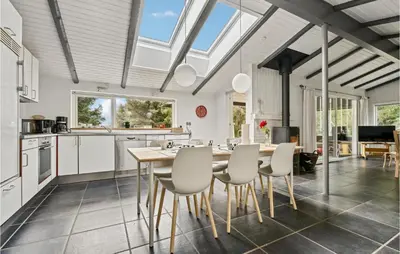 a kitchen with white cabinets and a table and chairs at Strandbo in Thyholm
