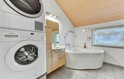 a bathroom with a washing machine and a bath tub at Holiday Home Kildebakken Vinderup V in Vinderup
