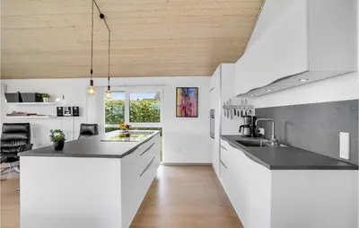 a kitchen with white cabinets and a wooden ceiling at Holiday Home Kildebakken Vinderup V in Vinderup