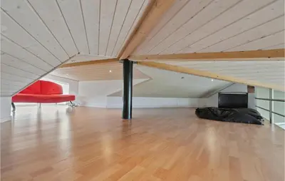 a room with a red chair and a couch in a attic at Holiday Home Lerskrænten Vinderup Xi in Vinderup