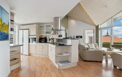 a kitchen with white cabinets and a couch and a table at Holiday Home Lerskrænten Vinderup Xi in Vinderup