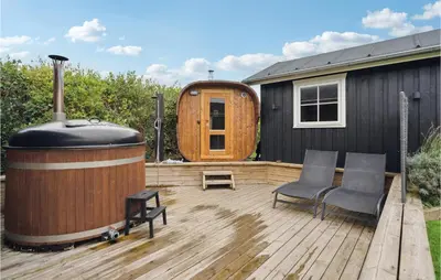 a large wooden deck with a barrel and two chairs at Holiday Home Lerskrænten Vinderup Xi in Vinderup