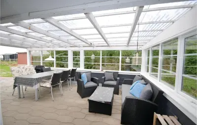 a screened in patio with furniture and tables and windows at Holiday Home Lærkevej Vinderup Xii in Vinderup