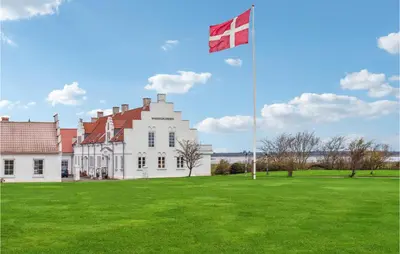 a large white building with a flag on a field at Bakkegården in Vesløs