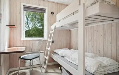 a bunk bed in a room with a ladder and a chair at Holiday Home Limfjordsvangen Snedsted X in Snedsted