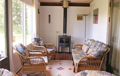 a living room with wicker chairs and a wood stove at Holiday Home Kraghøjvej Nykøbing M Ix in Hesselbjerg