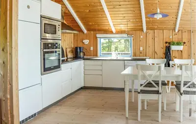 a kitchen with white cabinets and a table and chairs at Holiday Home Sulevej Hurup Thy Xi in Sindrup