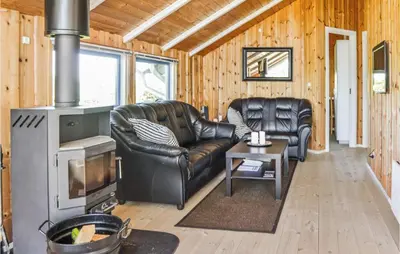 a living room with a leather couch and a stove at Holiday Home Sulevej Hurup Thy Xi in Sindrup